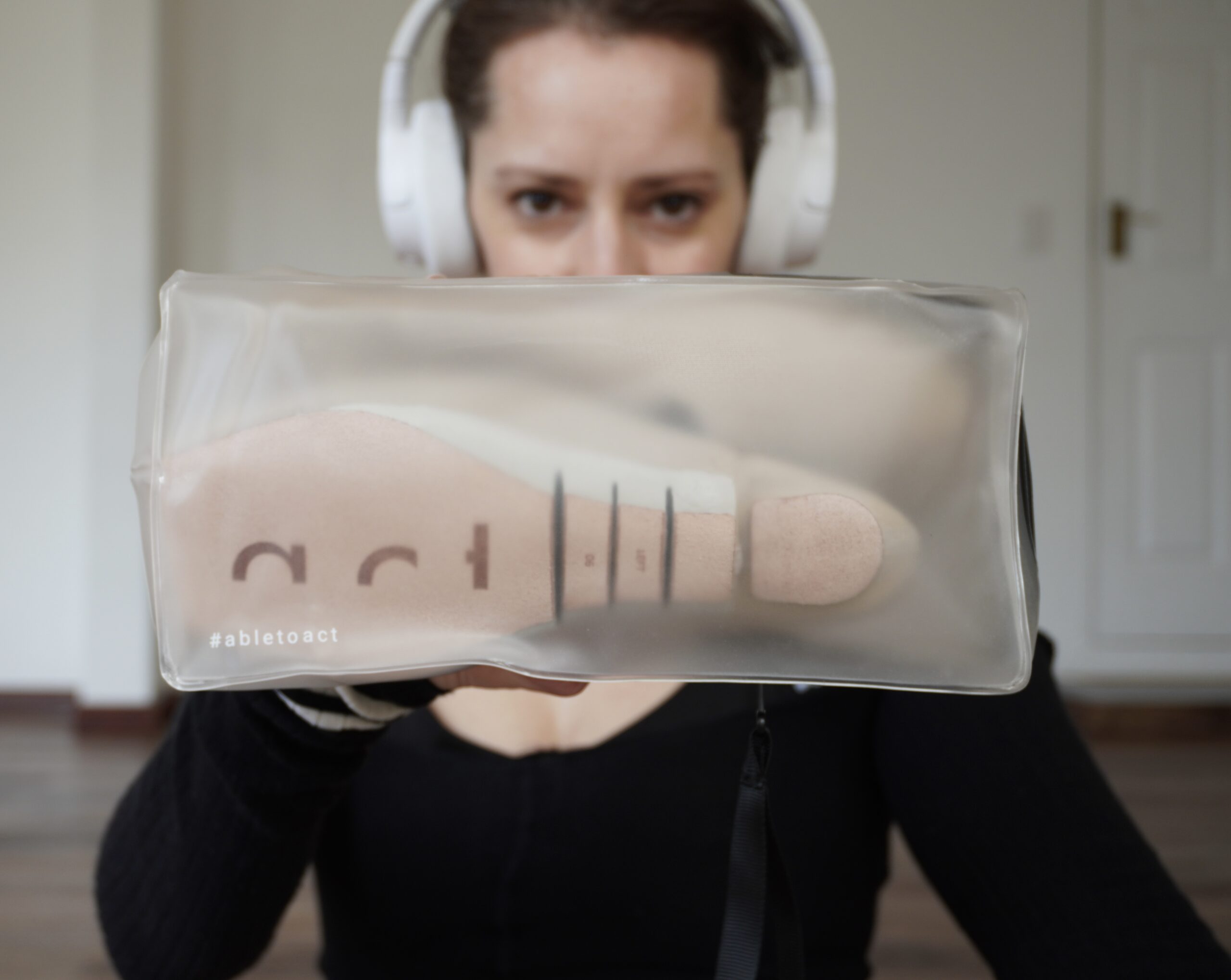 Ballet dancer wearing white headphones and holding Act Pointe Shoes